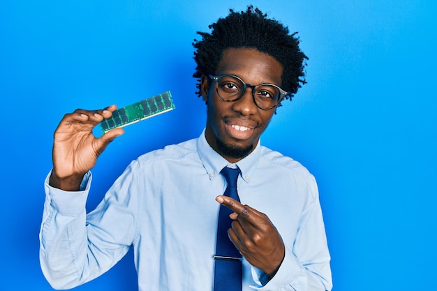 Young african american man holding computer ram smiling happy pointing with hand and finger