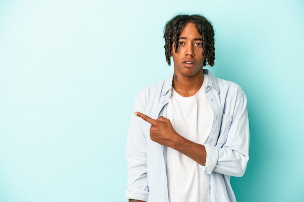 Young african american man isolated on blue background pointing to the side