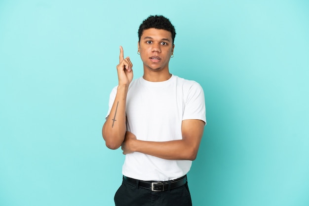 Young African American man isolated on blue background thinking an idea pointing the finger up