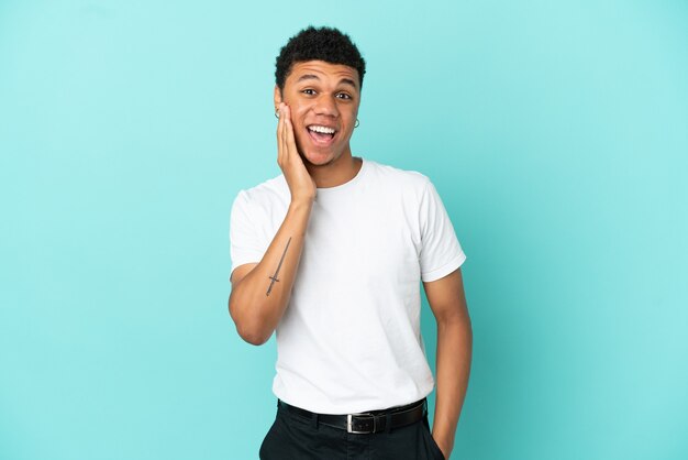 Young African American man isolated on blue background with surprise and shocked facial expression