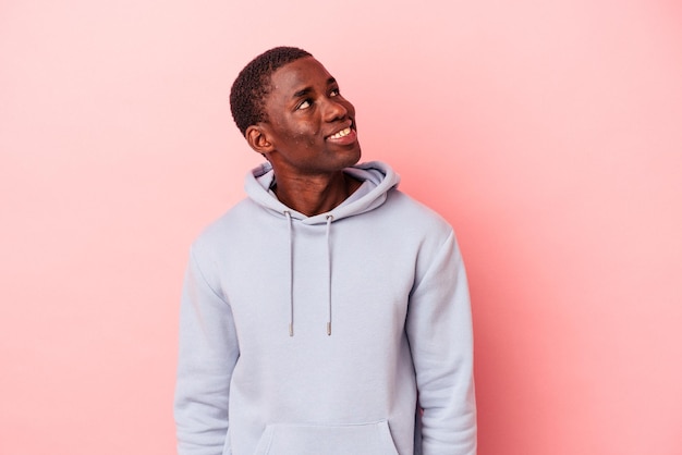 Young African American man isolated on pink background relaxed and happy laughing neck stretched showing teeth