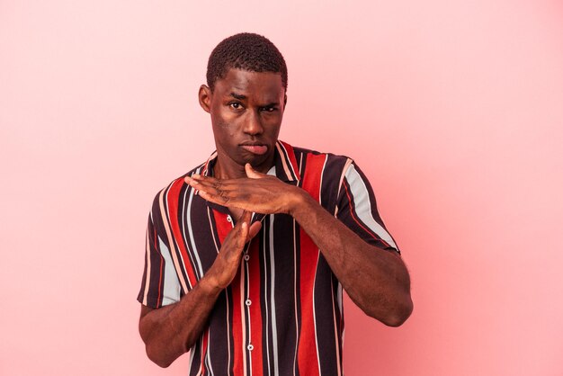 Young African American man isolated on pink background showing a timeout gesture