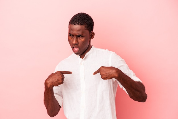 Young African American man isolated on pink background surprised pointing with finger, smiling broadly.