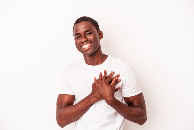 Young African American man isolated on white background has friendly expression, pressing palm to chest. Love concept.