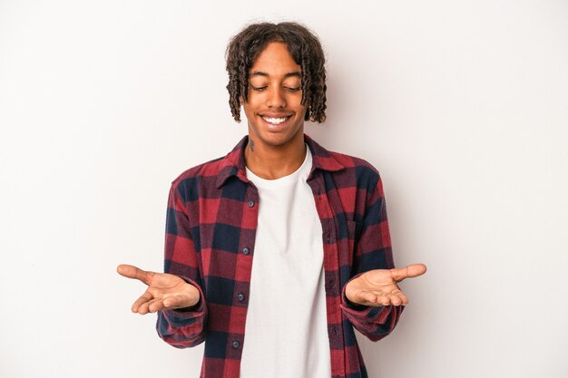 Young african american man isolated on white background holding something with palms, offering to camera.