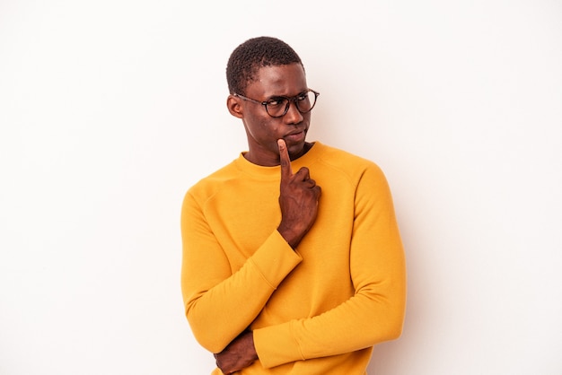 Young African American man isolated on white background looking sideways with doubtful and skeptical expression.