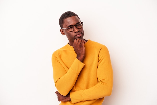 Young African American man isolated on white background looking sideways with doubtful and skeptical expression.