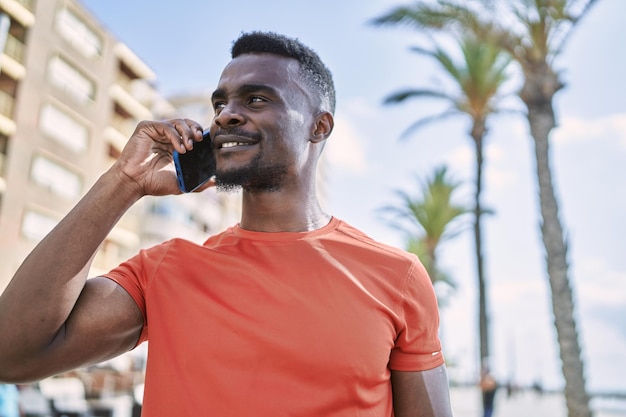 Young african american man smiling confident talking on the smartphone at street