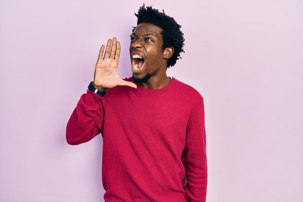 Young african american man wearing casual clothes shouting and screaming loud to side with hand on mouth. communication concept.