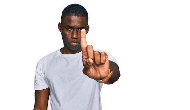 Young african american man wearing casual white t shirt pointing with finger up and angry expression showing no gesture