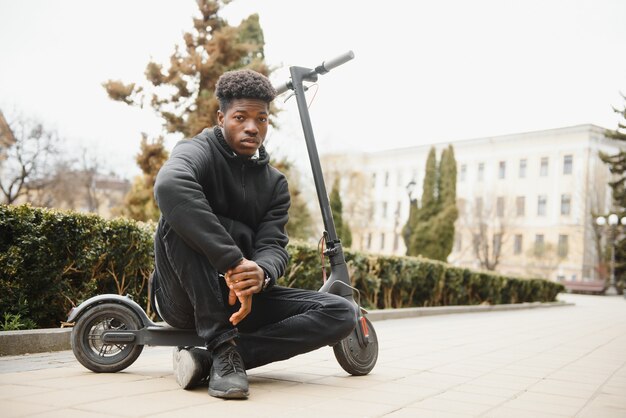 Young african-american man with electric scooter in the city