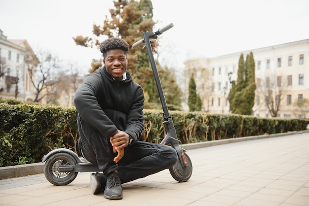 Young african-american man with electric scooter in the city