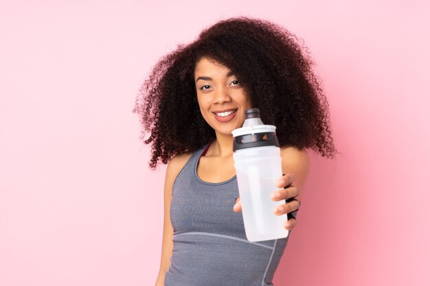 Young african american sport woman isolated on pink with sports water bottle