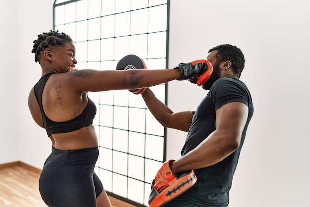 Young african american sporty couple boxing at sport center.