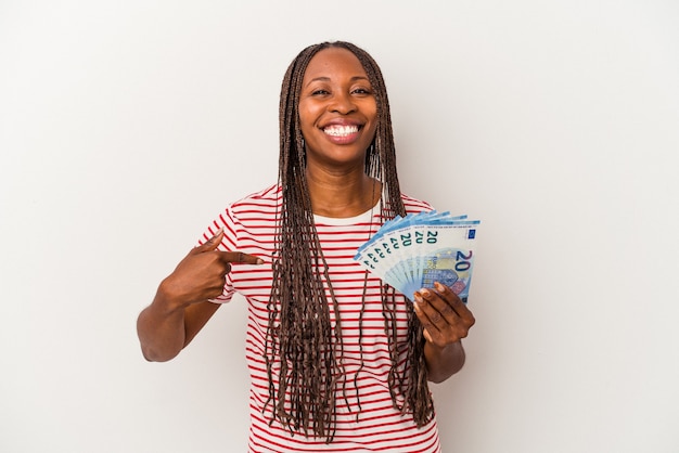 Young african american woman holding banknotes isolated on white background person pointing by hand to a shirt copy space, proud and confident