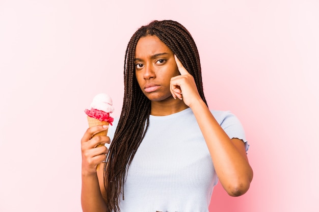 Young african american woman holding an ice cream isolated pointing temple with finger, thinking, focused on a task.