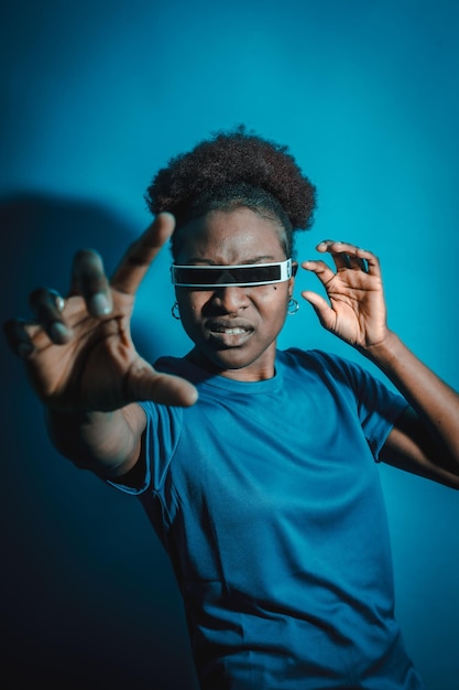 Young African American woman isolated on a blue background with futuristic glasses studio shoot future concept