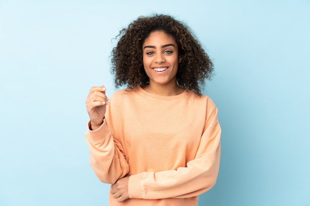 Young African American woman isolated on blue laughing