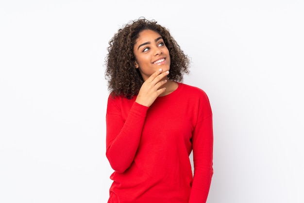 Young African American woman isolated on looking up while smiling