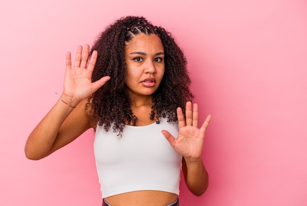 Young african american woman isolated on pink background being shocked due to an imminent danger