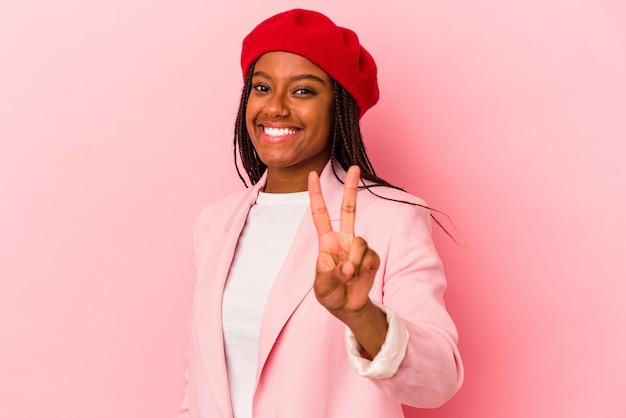 Young african american woman isolated on pink background  joyful and carefree showing a peace symbol with fingers.