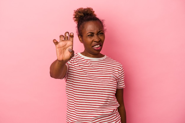 Young african american woman isolated on pink background showing claws imitating a cat, aggressive gesture.