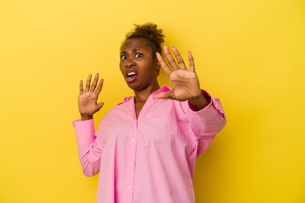 Young african american woman isolated on yellow background being shocked due to an imminent danger