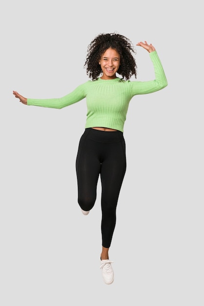 Young african american woman jumping with energy isolated