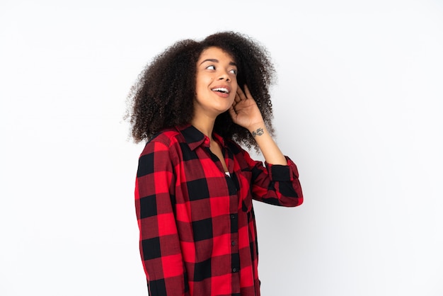 Young african american woman listening to something by putting hand on the ear