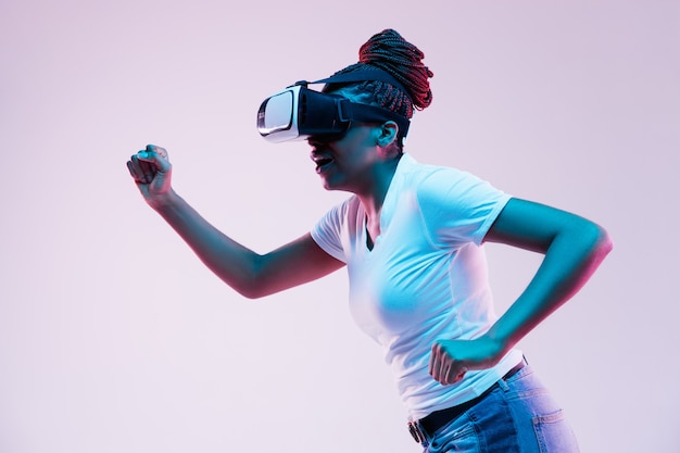 Young african-american woman's using VR-glasses in neon light