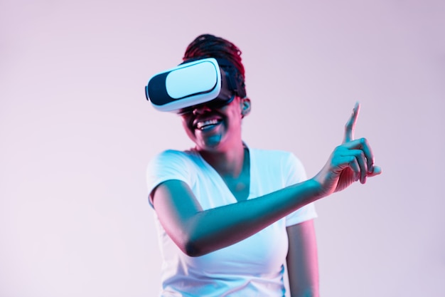 Young african-american woman's using VR-glasses in neon light