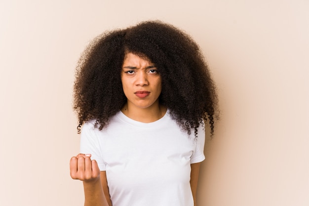 Young african american woman showing fist to camera, aggressive facial expression.