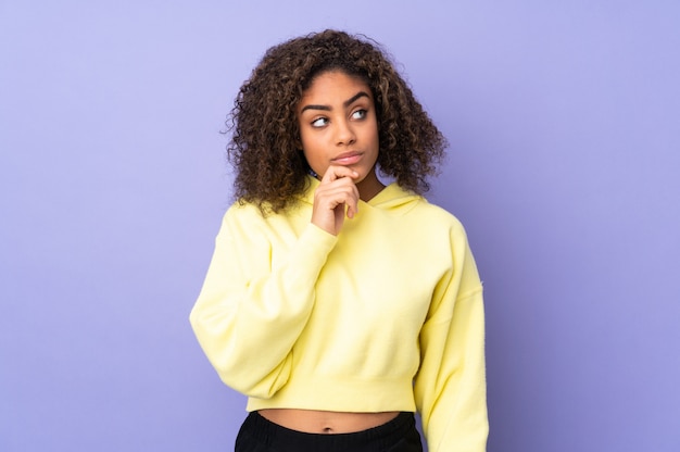 Young African American woman on wall having doubts and with confused face expression