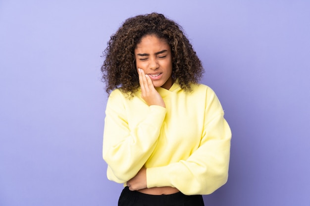 Young African American woman on wall with toothache