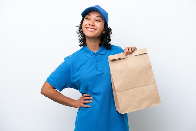 A young african american woman wearing a blue uniform is holding a brown paper bag