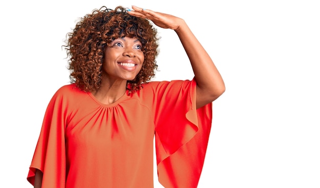 Young african american woman wearing casual clothes very happy and smiling looking far away with hand over head searching concept