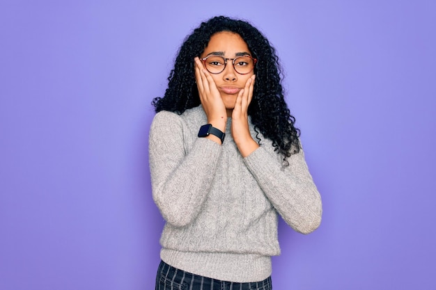 Young african american woman wearing casual sweater and glasses over purple background Tired hands covering face depression and sadness upset and irritated for problem