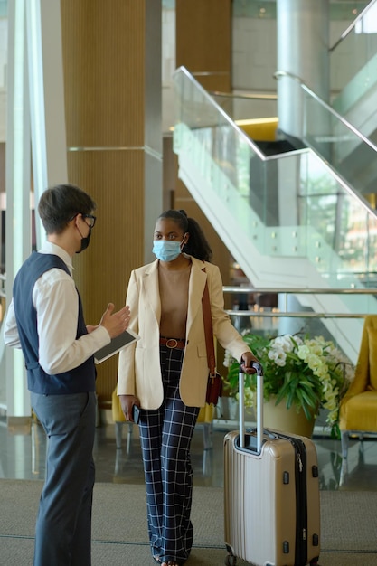 Young african american woman with baggage listening to male receptionist