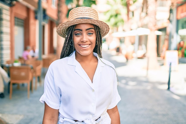 Young african american woman with braids smiling happy outdoors on a sunny day of summer