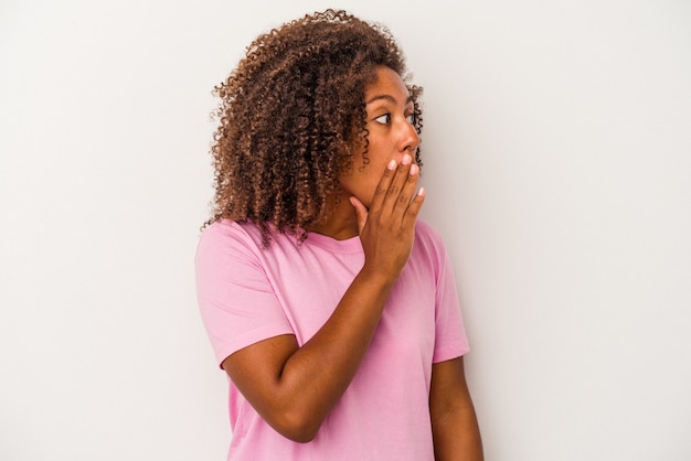 Young african american woman with curly hair isolated on white background being shocked because of something she has seen.