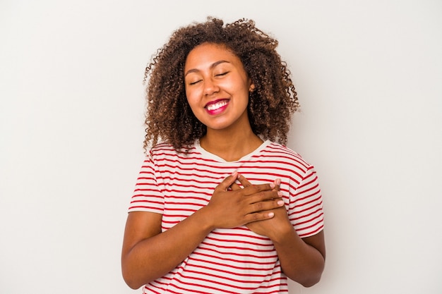 Young african american woman with curly hair isolated on white background laughing keeping hands on heart, concept of happiness.