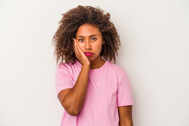 Young african american woman with curly hair isolated on white background who feels sad and pensive, looking at copy space.