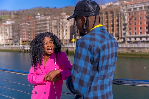 Young African American women in the city friends lifestyle laughing by a river on vacation