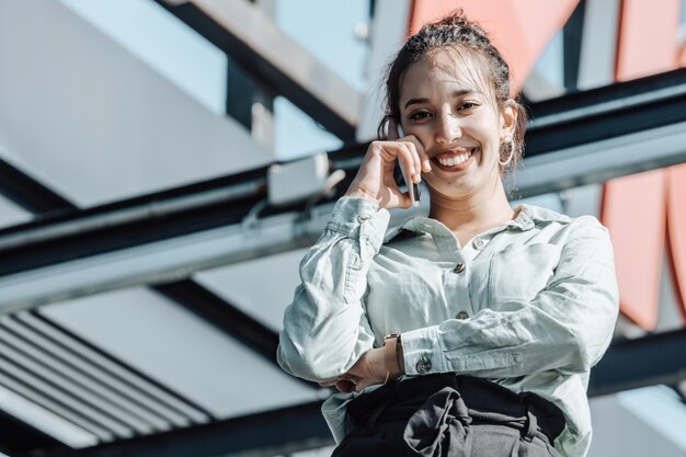 Young african arab business professional making a phone call outside office building during a sunny day.Dressed in stylish suit standing outdoors financial office,young woman lawyer using smart phone