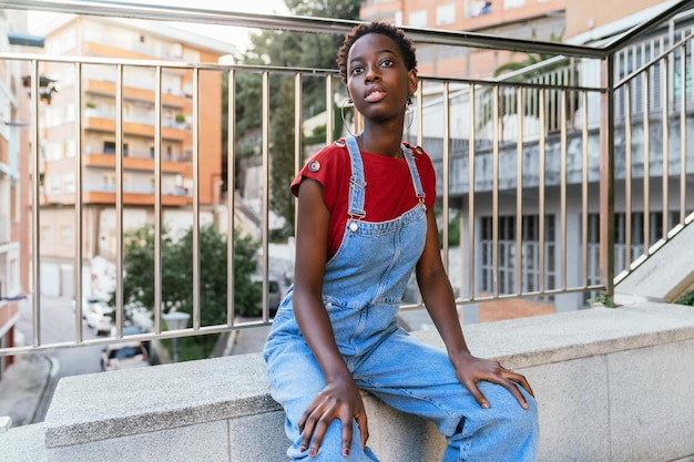 Young African black woman model posing sitting on the street in a city