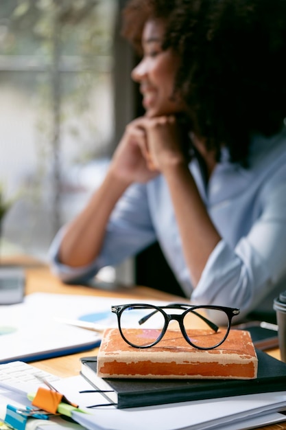 Young african black woman sitting at office with paperwork and glasses on the table