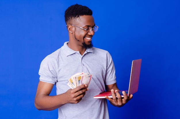 Young african businessman holding a lot of money and using his laptop