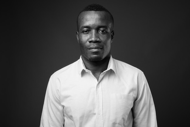 young African businessman wearing shirt against gray wall. black and white