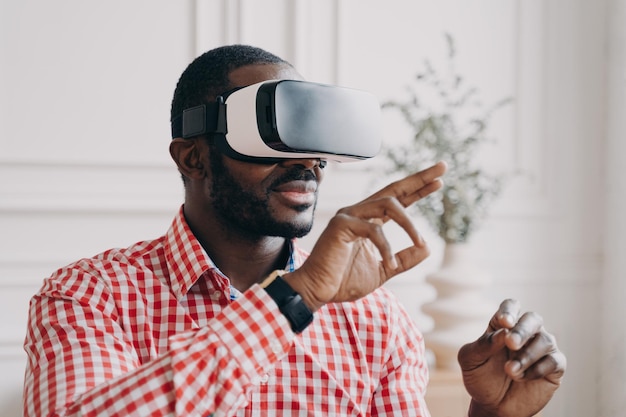 Young african businessman wearing VR glasses touching 3d objects interacting with virtual reality