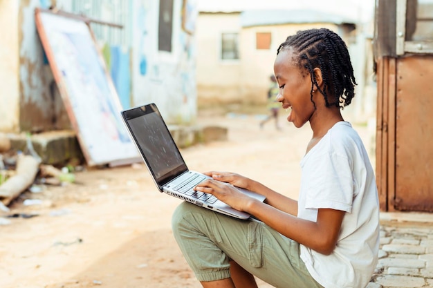 Photo young african child using a laptop on the ground while filled with excitement